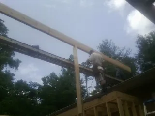 Carpenter setting a ridge beam over a new addition frame — Ice Dam Removal by Roofing Brothers in Bancroft