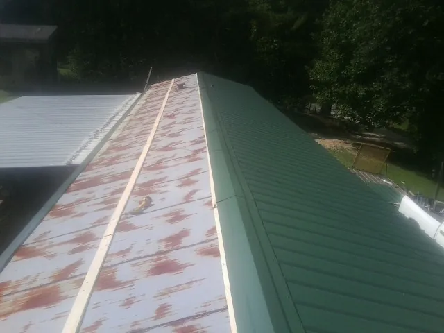 Old rusted panels beside newly installed green metal roofing — Wind Damage Roof Repair by Roofing Brothers in Bancroft
