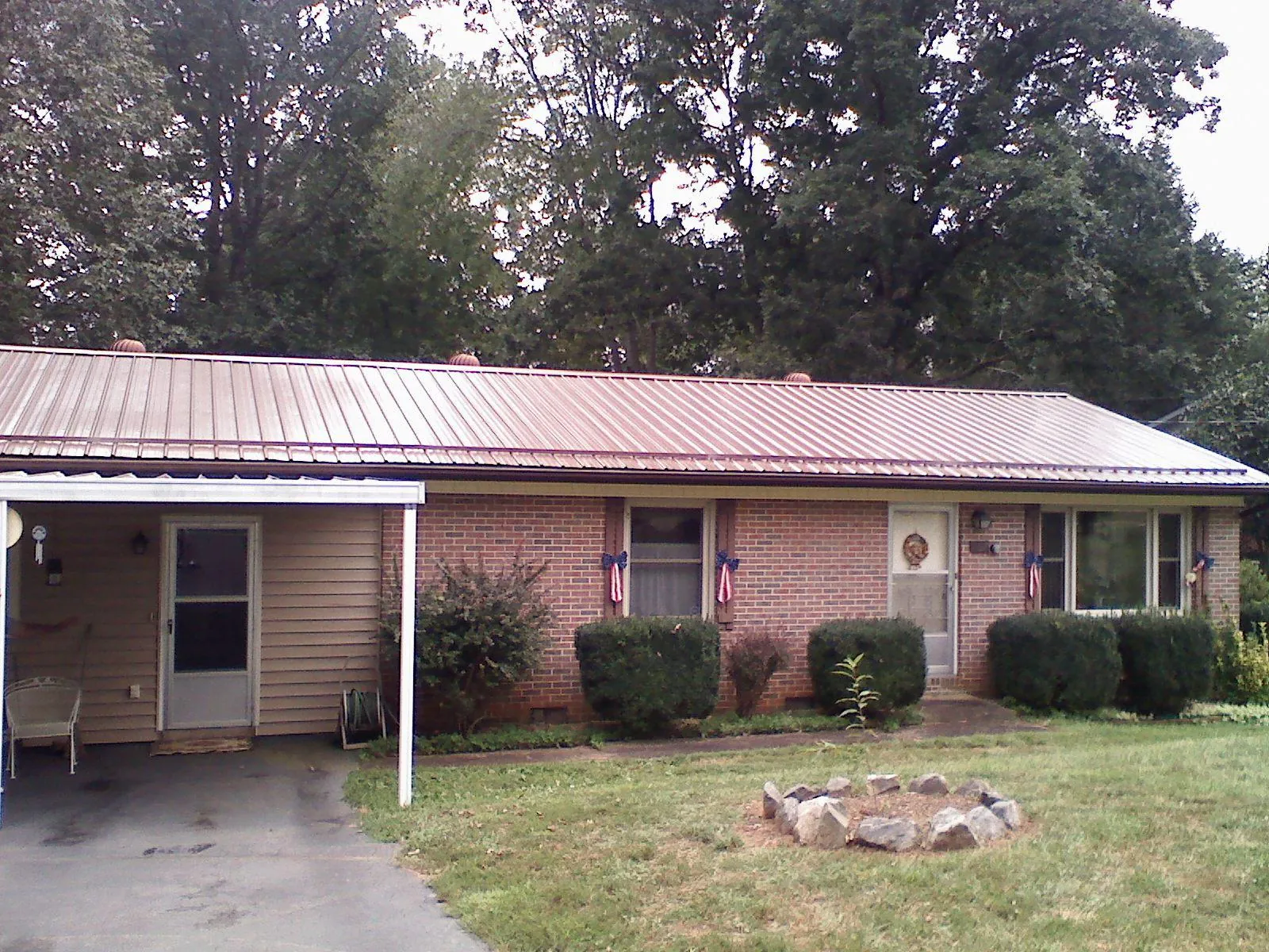 Bronze metal roof and carport on a brick ranch home — Roof Repair work by our crew in Bancroft