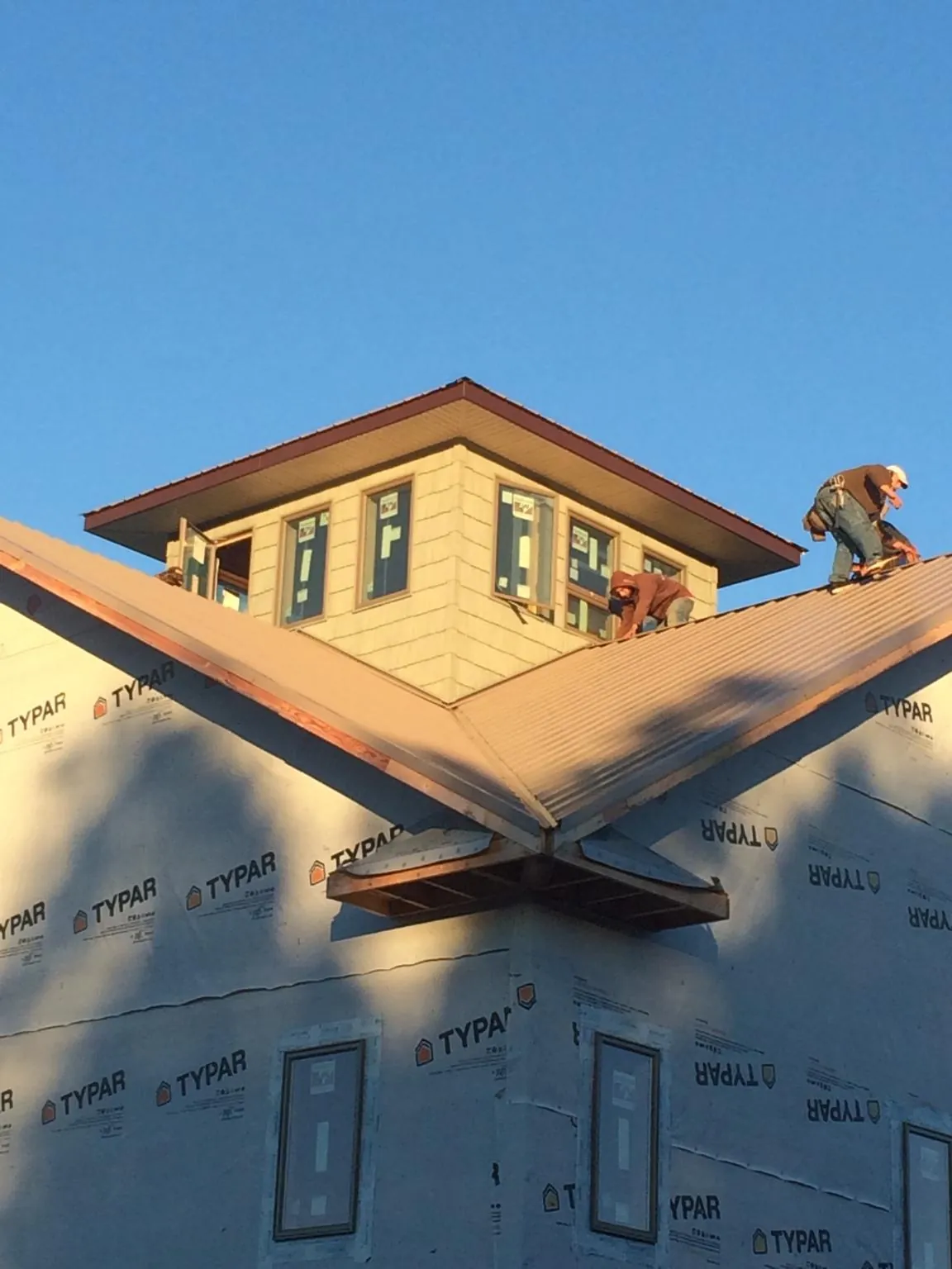 Roofers working around a rooftop cupola on a new metal roof at sunset — Roof Waterproofing in Bancroft by Roofing Brothers